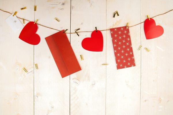 Red hearts and envelopes hanging on cord on wooden background